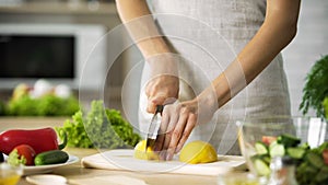 Female chef cutting lemon with sharp knife for lunch preparing, cooking tips