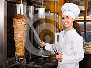 Female chef cutting meat for shawarma