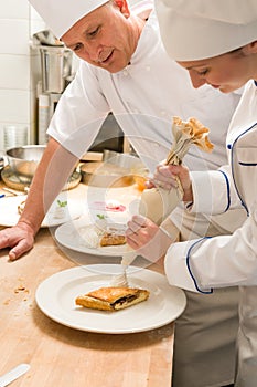 Female chef decorating cake with whipped cream