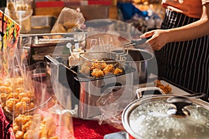 Female chef deep fried meat ball in kitchen.