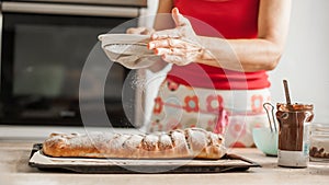 Female chef finishing sweet cake with sugar on the top