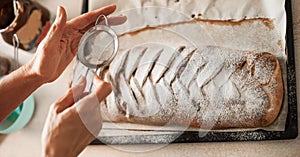 Female chef finishing sweet cake with sugar on the top