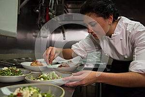 Female chef garnishing appetizer plates at order station photo