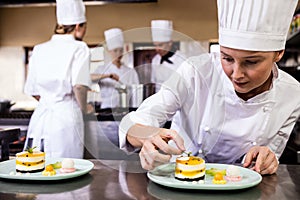 Female chef garnishing delicious desserts in a plate