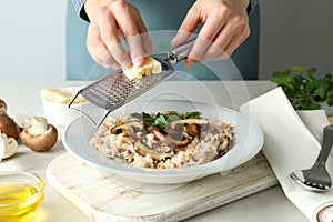 Female chef grate cheese on risotto with mushrooms
