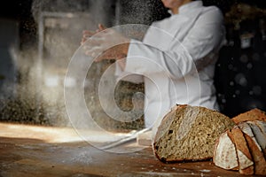 Female chef hands clapping in cloud of powdery flour over table