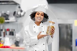female chef holding jar with pasta in kitchen
