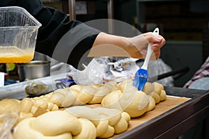 Female chef lubricate the bakery products with an egg yolk. Cook