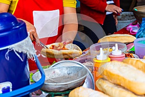 Female chef making Laos style baguette or French bread sanwich, a highly popular breakfast street food in Laos