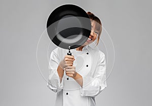 female chef peeking out from behind frying pan