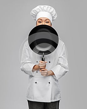 female chef peeking out from behind frying pan