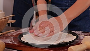 Female chef prepares dough to make homemade Italian pizza.