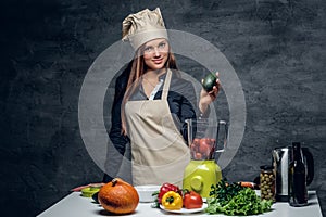 Female chef preparing vegetable juice in a blender.