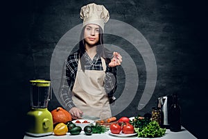 Female chef preparing vegetable juice in a blender.