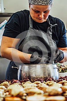 Female Chef Putting Ingredients of Burgers on a Sliced Bread Spread on a Table in Black Gloves - Concept of the Hard Working