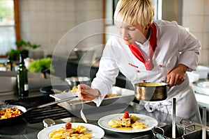 Female chef in a restaurant or hotel kitchen cooki photo