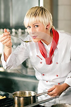 Female Chef in a restaurant kitchen tasting