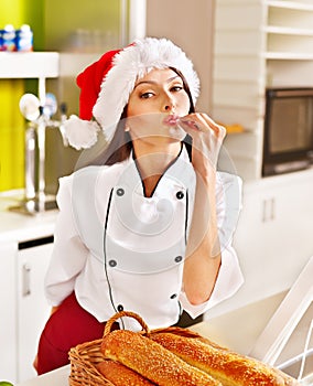 Female chef in Santa hat holding food.