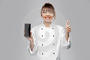 female chef with smartphone showing thumbs up