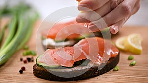 Female chef squeeze lemon over sandwich with smoked salmon