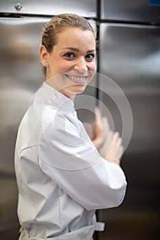 female chef stood by stainless-steel industrial fridge