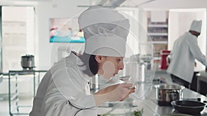 Female chef tasting liquid sauce on stove to make cuisine dish