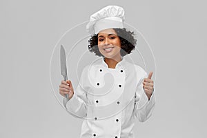 female chef in toque with knife showing thumbs up