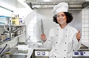 female chef in toque with knife showing thumbs up