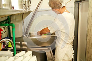 Female chef and worker is working at ice cream factory is pouring pasteurized milk and cooking mixing milk.