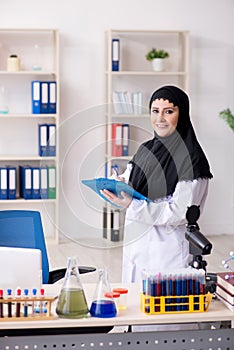 The female chemist in hijab working in the lab