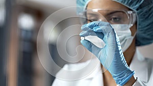 Female chemist looking at white pill, new medication testing in laboratory