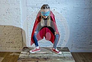 Female child 7 or 8 years old young girl performing happy and excited posing wearing cap and mask in super hero fantasy costume lo
