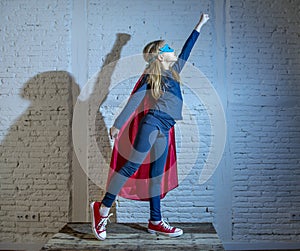 Female child 7 or 8 years old young girl performing happy and excited posing wearing cap and mask in super hero fantasy costume lo