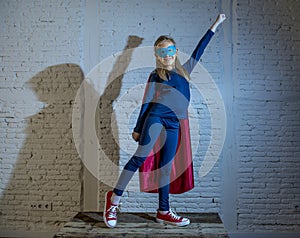 Female child 7 or 8 years old young girl performing happy and excited posing wearing cap and mask in super hero fantasy costume lo
