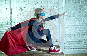 Female child 7 or 8 years old young girl performing happy and excited posing wearing cap and mask in super hero fantasy costume lo