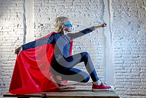 Female child 7 or 8 years old young girl performing happy and excited posing wearing cap and mask in super hero fantasy costume lo