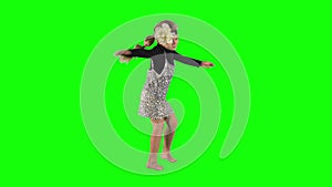 Female child with blond hair turning around and dancing on green background