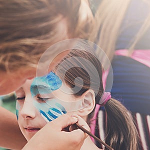Female child face painting, making butterfly process