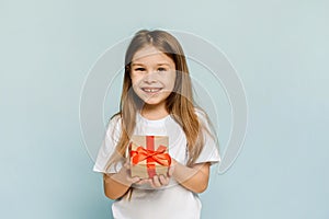 A female child holds a box with a Christmas present in her hand.  on blue background