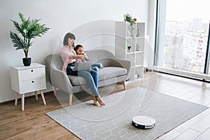 Female and child with laptop using cleaning device at home