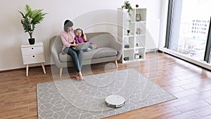 Female and child with laptop using cleaning device at home