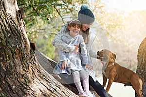 Female child, mother and playing in park with pet, trees and happiness in winter. Family, daughter and pitbull in nature