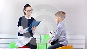 Female child psychologist making support discussing with little boy at therapy session