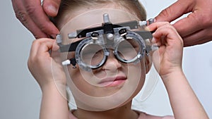Female child squinting eyes wearing optical trial frame, eye examination, myopia