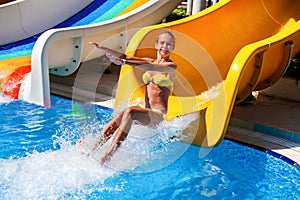 Female child on water slide at aquapark hand up.