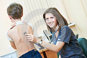 Female children`s pediatrician doctor during little boy examination