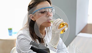 Female chimist in white protective gloves drink beer