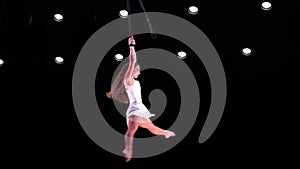 Female circus artist on Aerial straps on black background performing spinning trick. Concept of individuality