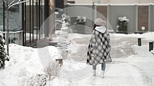 Female city dweller is walking outdoor at winter day, young woman dressed coat and hat