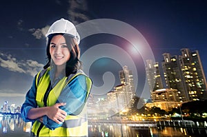 Female Civil Engineer with safety equipment with night modern city in the background for City Development cocept